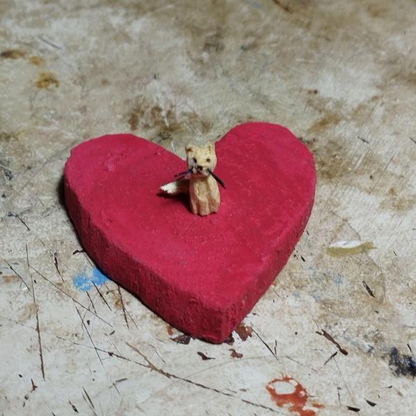 Un mini chat en bois posé sur un coeur rouge