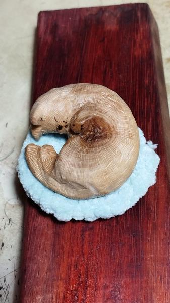 Un chat en bois qui dort sur un coussin crocheté