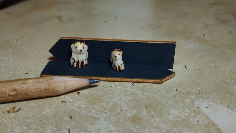 Deux mini sculptures de renard en bois. Elles sont à côté d'un crayon gris et pas beaucoup plus grandes que le crayon 