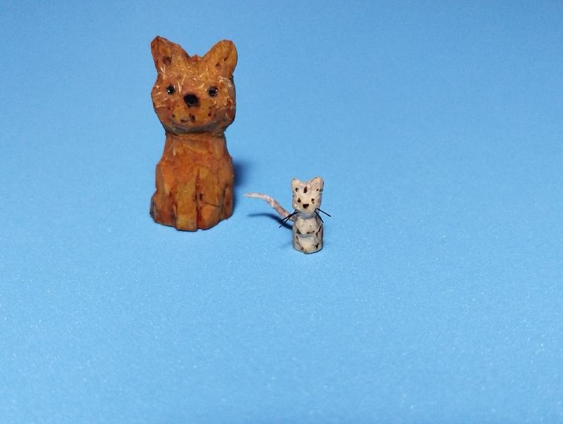Deux animaux en bois : un chat et une petite souris. La souris a des moustaches en nylon et une queue rose