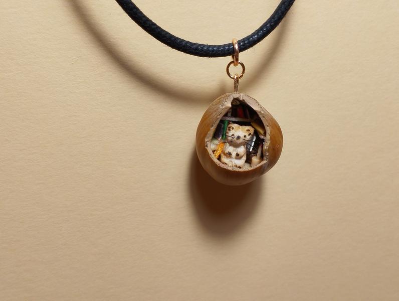 Un pendentif fait dans une noisette. On voit un petit rat