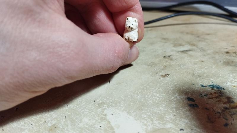 Petite sculpture de chat en bois tenue du bout des doigts 