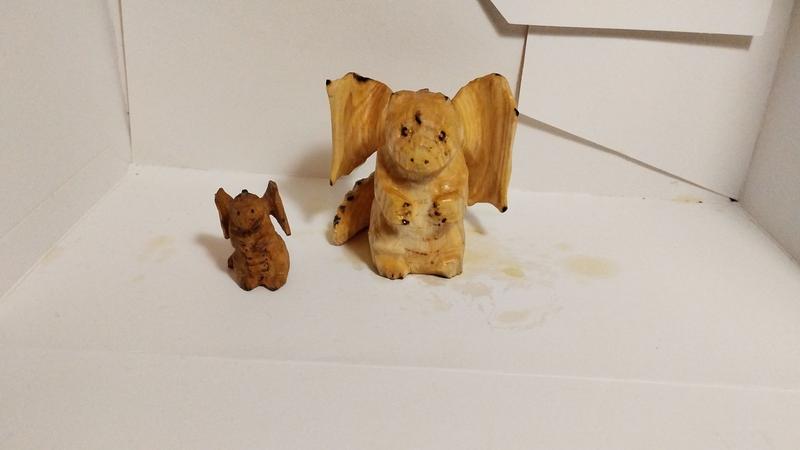 Deux dragons en bois vus de face. Un petit marron et un grand plus clair.