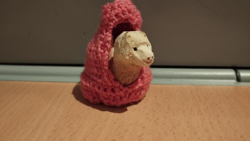 Un alpaga en bois dans un panier crocheté de couleur rose