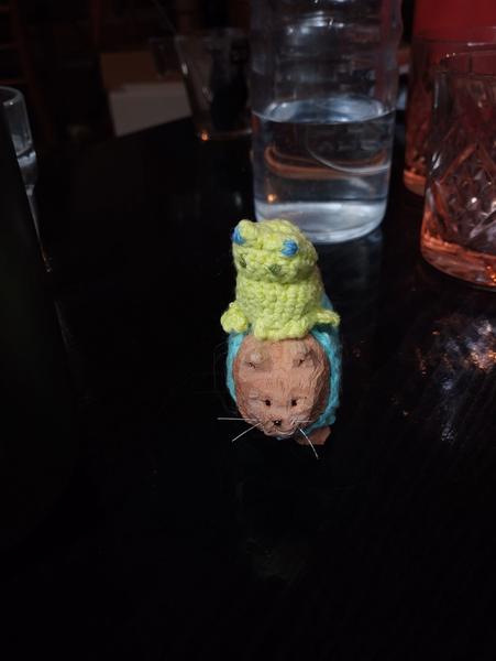 Une grenouille au crochet, regard énervé qui chevauche un chat en bois 