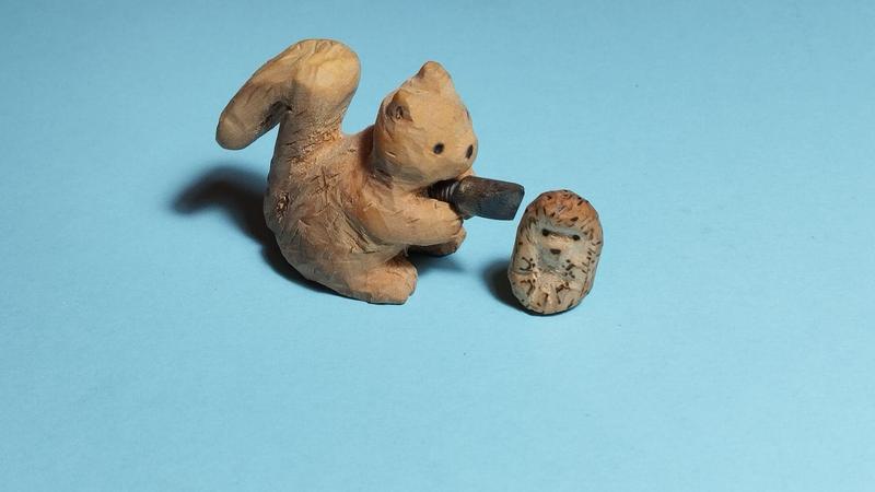 Deux sculptures en bois : un écureuil marque un petit hérisson avec une pointe de pyrogravure