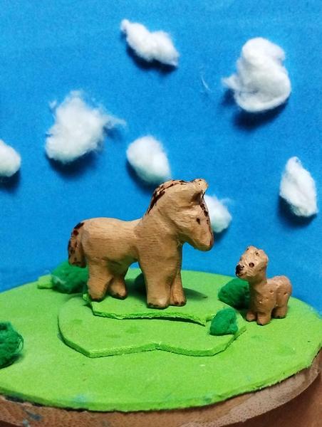 Un cheval et un alpaga en bois sur un décor en mousse de prairie