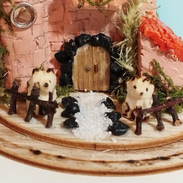 Gros plan sur la porte principale. Elle est cerclée par des pierres noires. Deux renards gardent l'entrée. Ils n'ont pas du tout l'air menaçant
