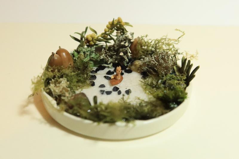 petite sculpture de chien posée sur une feuille dans un décor de mare