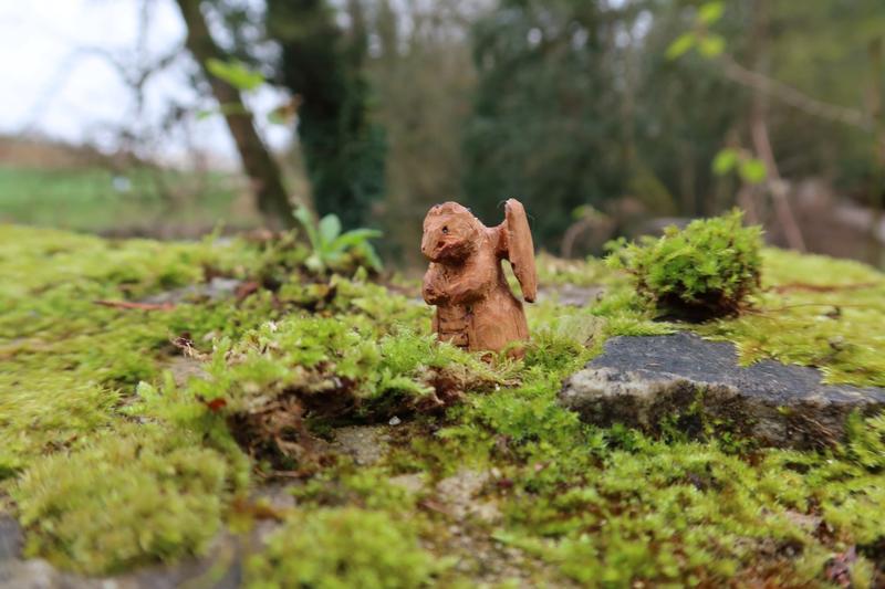 Petite sculpture de dragon en bois.Il regarde de la mousse