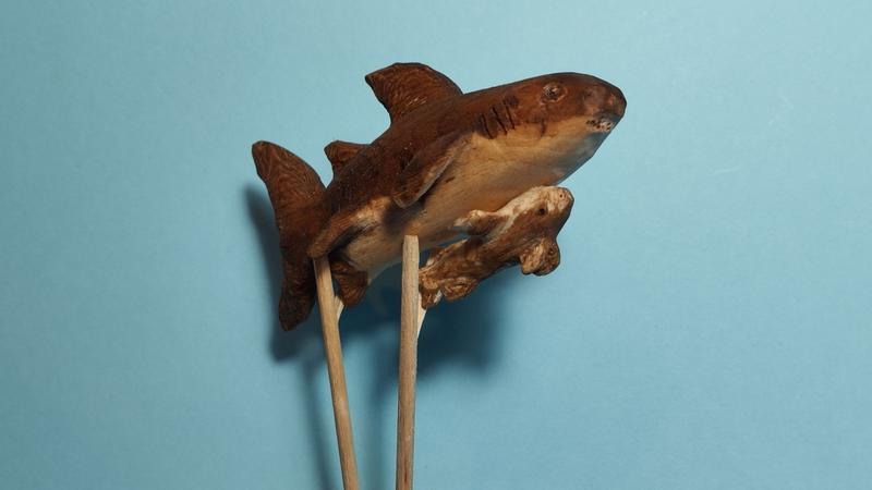 Un requin en bois, un remora est collé sous son ventre 