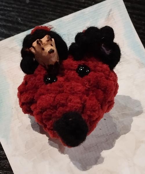 Un petit renard en bois posé dans l'oreille d'une tête de renard crochetée 