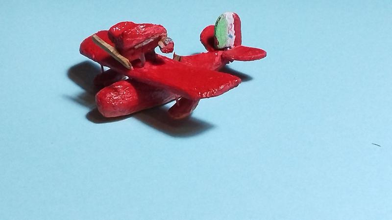 Un petit hydravion rouge en bois. Moteur à hélice. Un drapeau italien avec un r rouge est peint sur la dérive