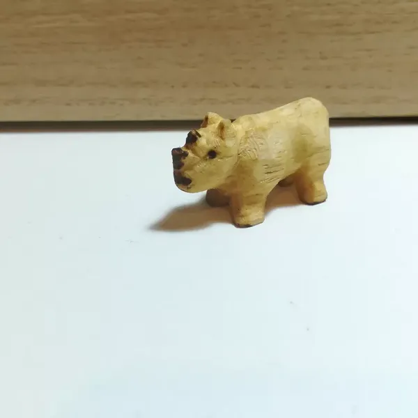 Un petit rhinocéros en bois. Le bois est jaune, les cornes et les yeux sont pyrogravés 
