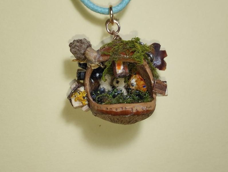 Un pendentif noisette assez chargé. A l'extérieur, des maisons, de la mousse. À l'intérieur, deux kodamas, un calcifer, des noiraudes et une lanterne 