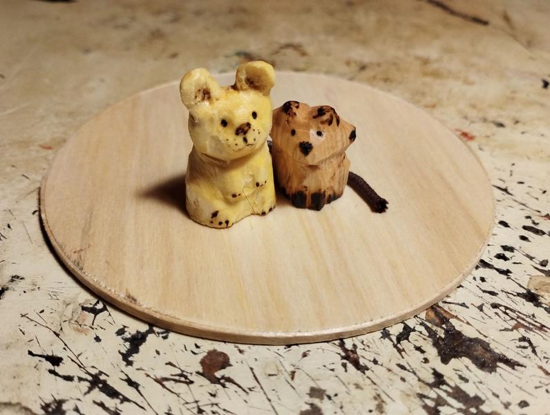 Deux sculptures en bois. Un rongeur à la tête très ronde et un renard plus petit. Les deux sont collés, la queue du rongeur contourne le renard