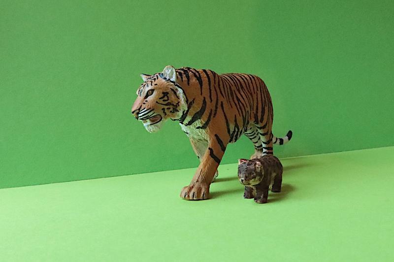 petite sculpture de tigre en bois à côté d'une figurine de tigre en plastique