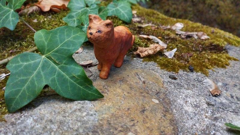 Un chat en bois, marchant à côté d'une feuille de lierre aussi grande que lui