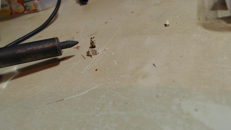 mini sculpture de renard en bois pyrogravé à côté de la pointe conique du pyrograveur. Le renard fait en hauteur 1.5 fois le diamètre de la partiee la plus large de la pointe