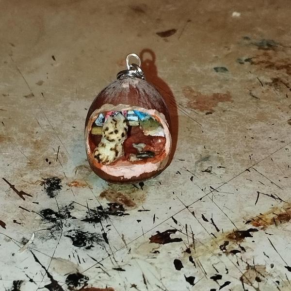 Un pendentif noisetteA l'intérieur, un chat tigré et une bibliothèque