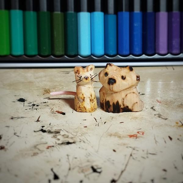 Une petite souris en bois et un renard. La souris a des moustaches en nylon et une queue rose. 