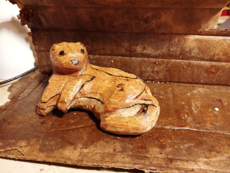 Sculpture de loutre en boisElle est allongée et regarde vers l'objectif 