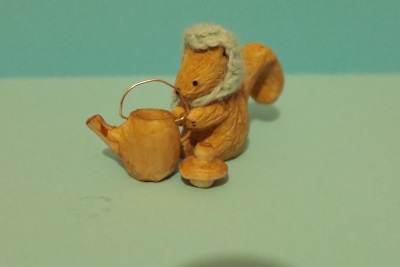 sculpture d'écureuil en bois à côté d'une théière en bois un peu plus petite que l'écureuille couvercle est posé à côté