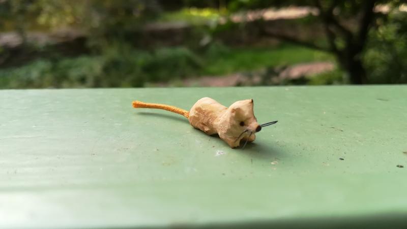 Une petite sculpture de rat avec des moustaches noires