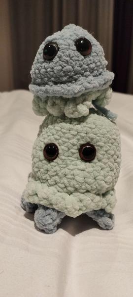Deux méduses en crochet l'une sur l'autre. La petite est majoritairement bleue et un peu verte. 'et contraire pour la plus grande