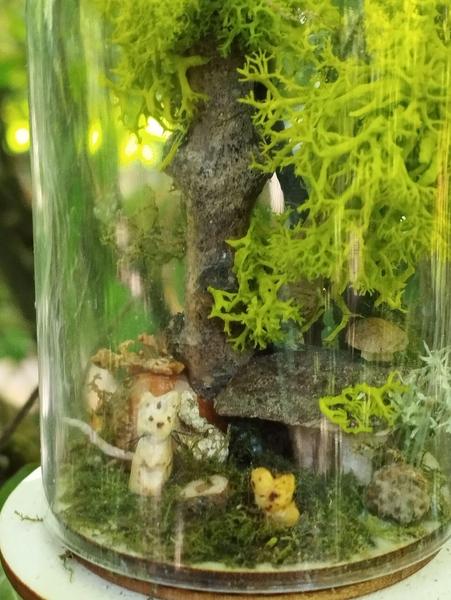 Gros plan sur le sol : une souris et un oiseau devant une maison collée contre l'arbre
