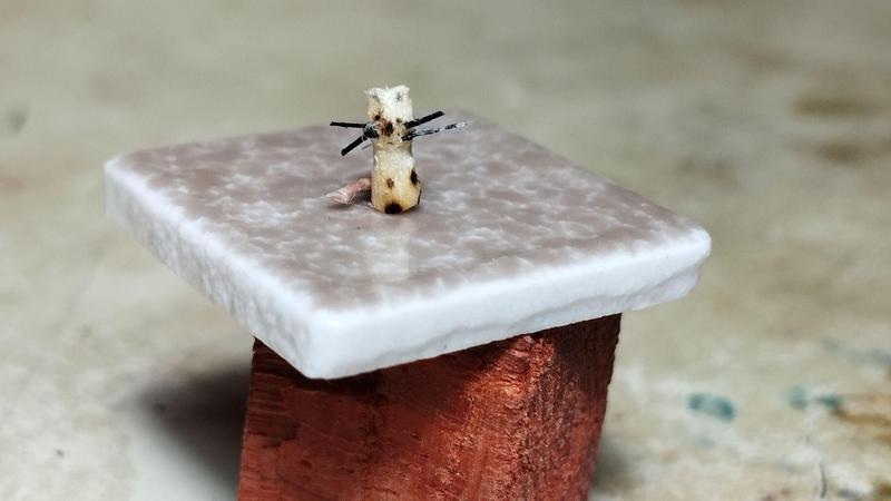 Une mini souris faite avec un morceau d'allumette, du nylon pour les moustaches et une queue rose pour la queue