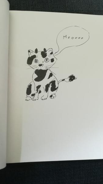 Drawing of a black and white cat that says "meoooo"The cat has black spots and two small horns
