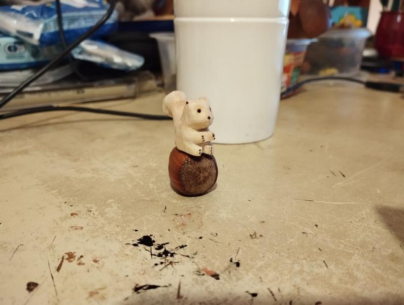Petit écureuil en bois posé sur une noisette 