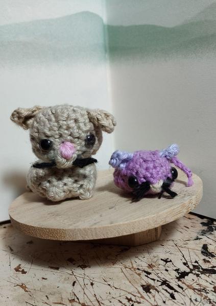 Un chat et une souris faits au crochet. Le chat est beige, la souris violette