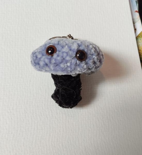 Un champignon au crochet. Chapeau violet, pied noir. Il a deux yeux