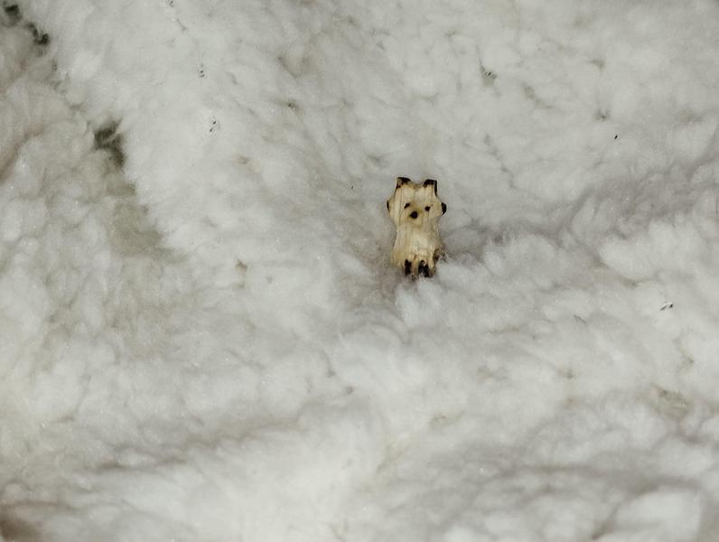 Un petit renard en bois au milieu d'un plaid duveteux