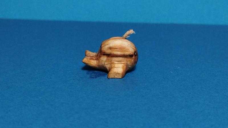 Une petite baleine en bois de profil. Son corps est très sphérique mises à part les nageoires