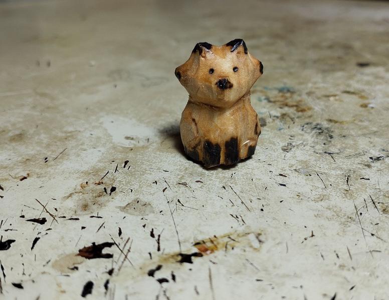 Un renard en bois, oreille, yeux, museau et pattes noircis