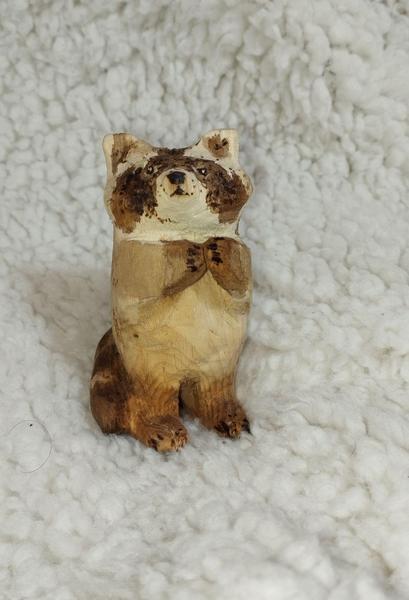 Sculpture d'un raton laveur en bois, debout en train de supplier de la nourriture
