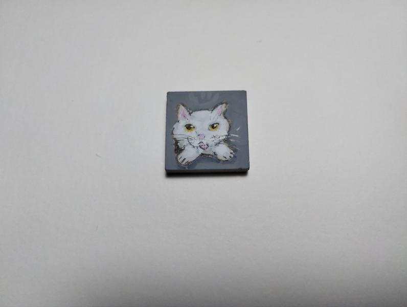 Petite peinture sur carré de mosaïque d'un chat blanc qui sort d'une case en tirant la langue 