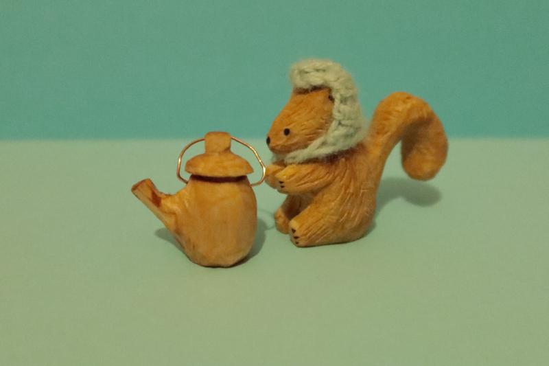 sculpture d'écureuil en bois à côté d'une théière en bois un peu plus petite que l'écureuil