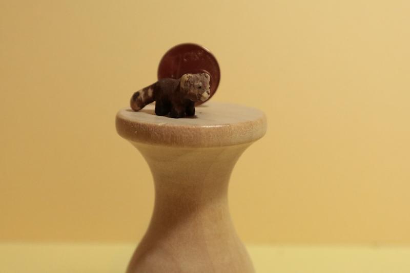 mini sculpture de panda roux devant une pièce de 1 centime
