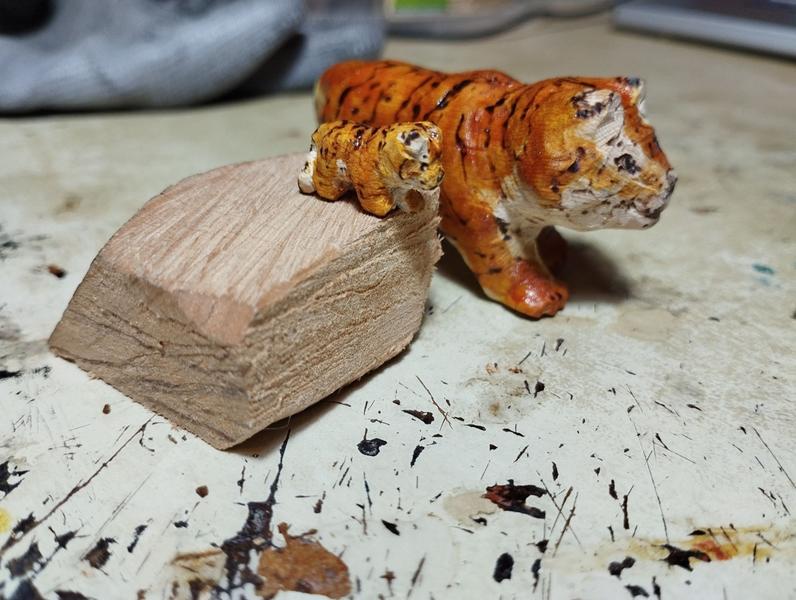 Deux tigres en bois, un grand et un petit. Le petit est sur un morceau de bois pour être à la hauteur du grand 