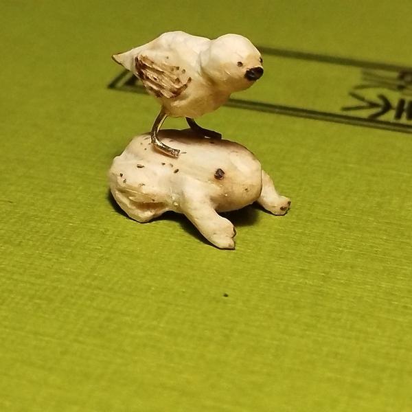 Un petit oisea6en bois posé sur une grenouille
