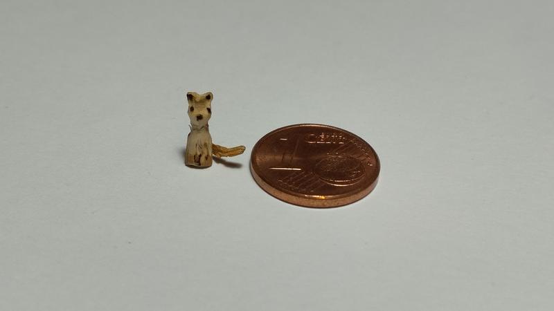 Un mini chien bois, à côté d'une pièce d'un centime. Il est plus petit et très fin