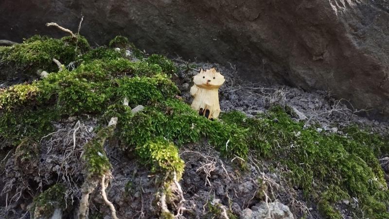 Un renard en bois, posé sur un parterre moussu