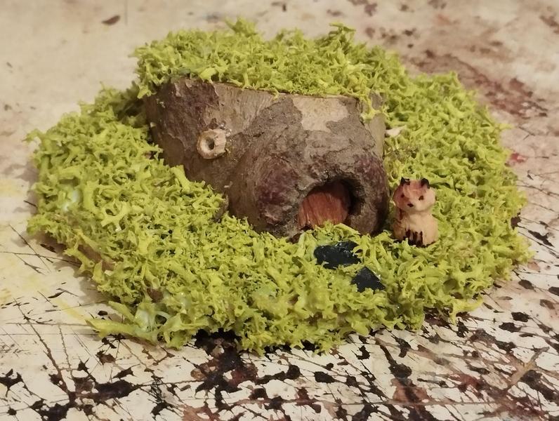 Une maquette de maison hobbit avec un mini renard. L'ensemble manque de détails, seule l'entrée rappelle une maison