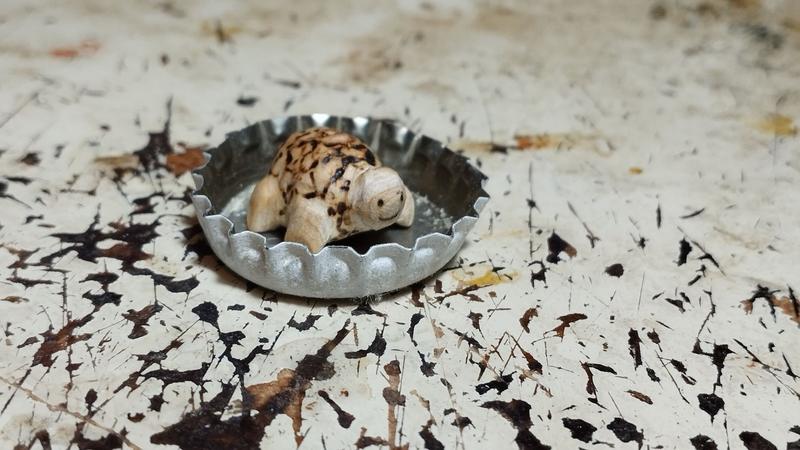 Une petite tortue en bois dans une capsule de bière