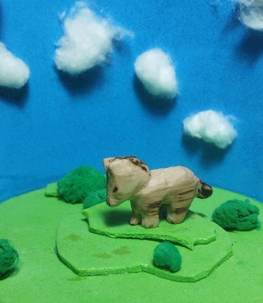 Un petit poney en bois qui broute son pré