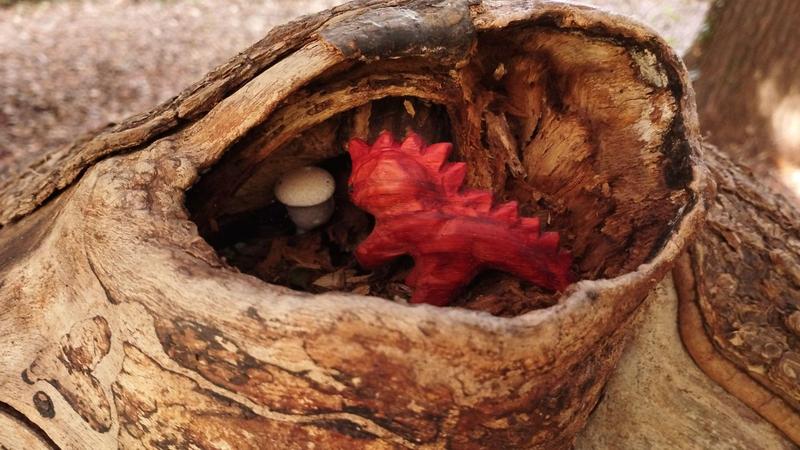 Le dino dans une souche d'arbre. Il admire un champignon